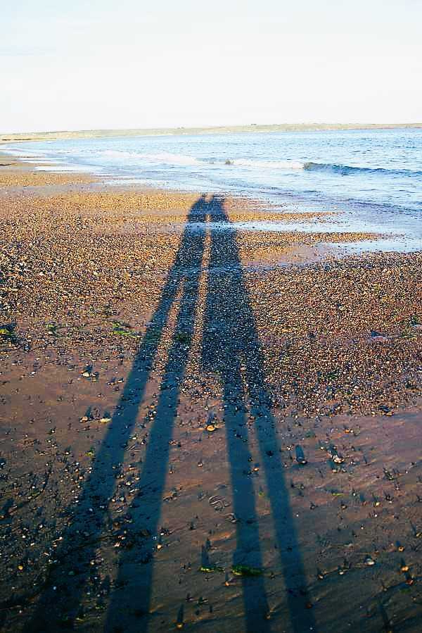 Sunset shadow on the beach of two people in the sand, image about the couple behind Irelands West Coast blog