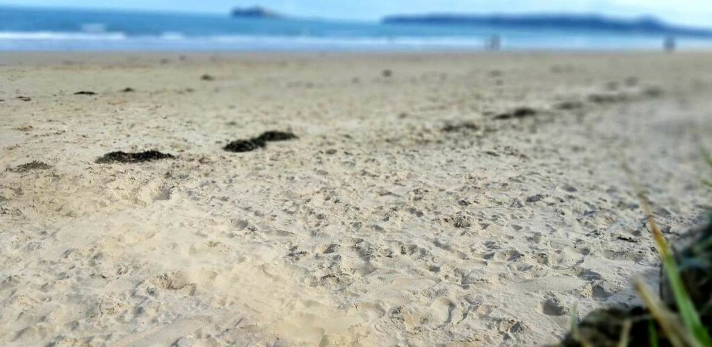 Belderra Strand on Mullet Peninsula, yellow sand with a line of footprints, blue sea in background