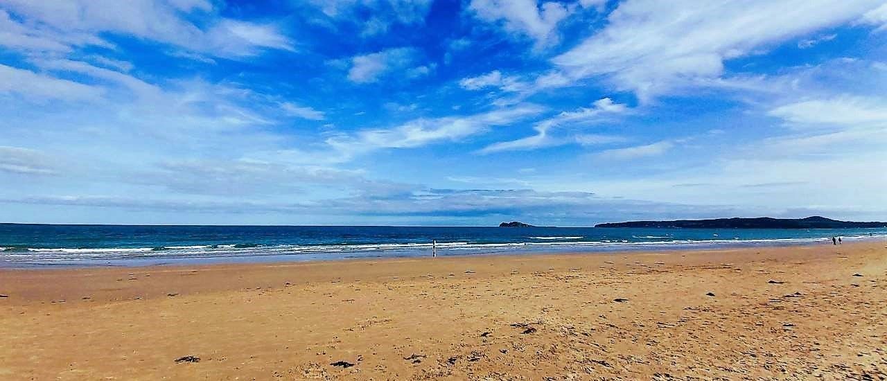 View of Belderra Strand on Mullet Peninsula, yellow sand, blue sea and white clouds