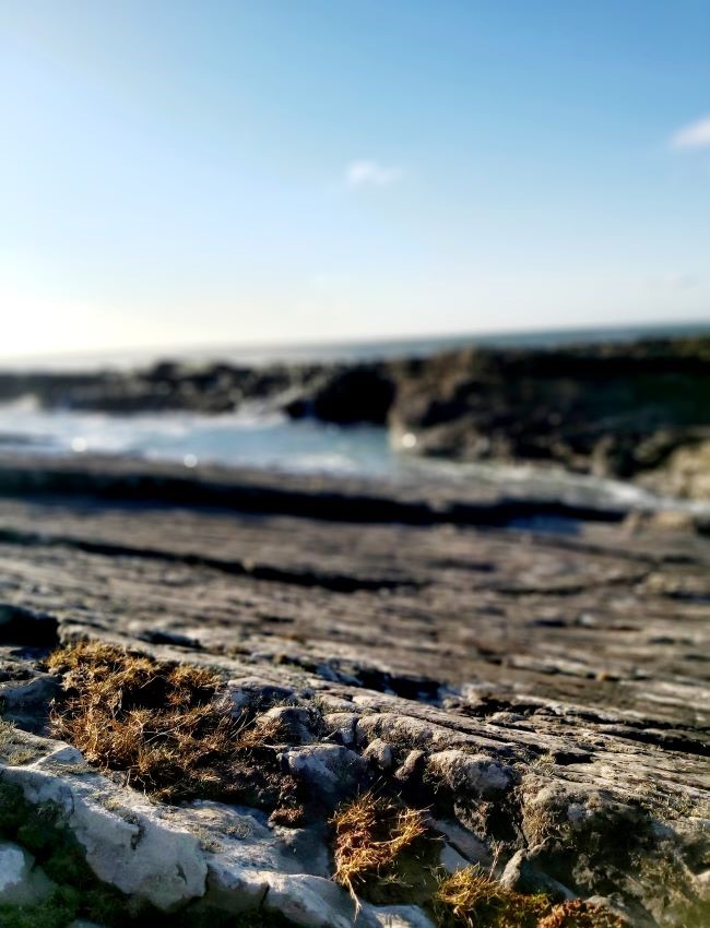 Close up on a rockface at the bridges of ross with sea foam on the left side and the sea out of focus in the background