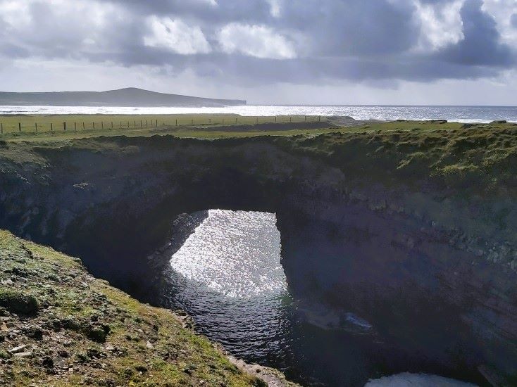 bridges of ross in county clare in sunset - rocky arch across the seapool, sea and sky in background