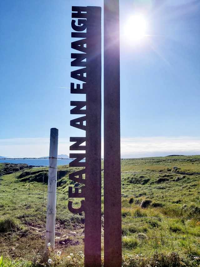 Metal sign of wild atlantic way marking annagh head, against grass and sea