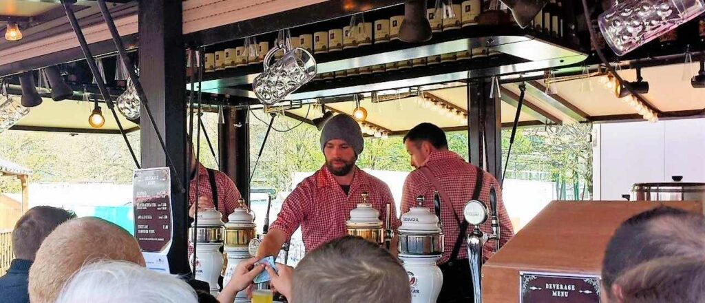 mobile beer stand serving a line of people, beer taps and two barmen