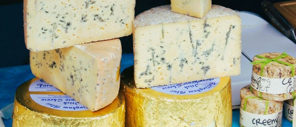 wheels of blue cheeses stacked on top of each other at a farmers market food festival