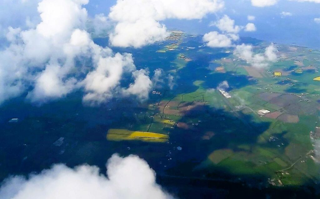 travel to Ireland's west coast by plane - view from a plane window at green land below, sea and white clouds