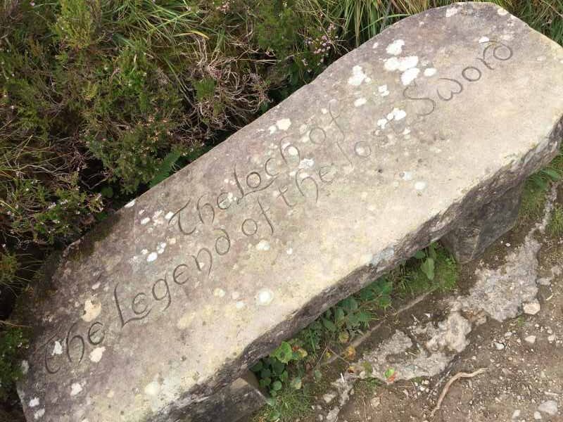 Long flat stone by the road with inscription Loch of the Legend of the Lost Sword. West Highland Way