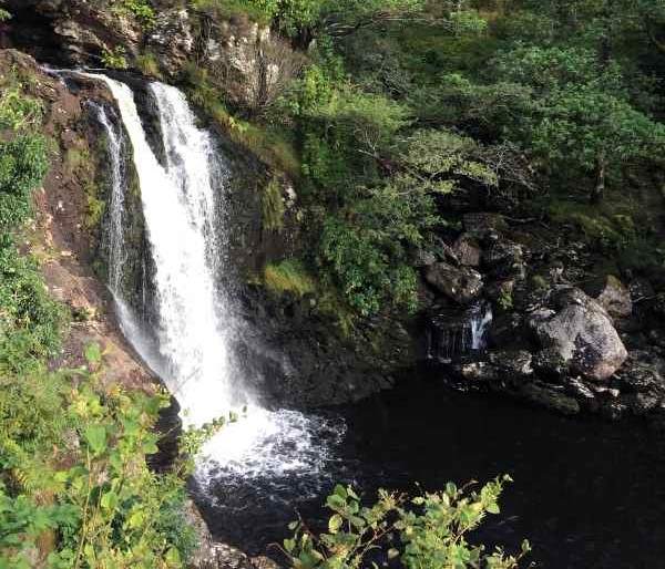 Waterfall by Loch Lomond on the West Highland Way surrounded by green trees